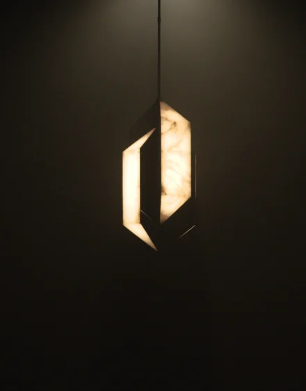 Freeze frame of a video, shows a unique light hanging in a dark room.